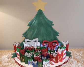May include: A wooden Christmas tree advent calendar with 24 numbered doors decorated with glitter and bows. The doors are shaped like presents and are arranged in a circle around the tree. The tree is green and has a gold star on top.