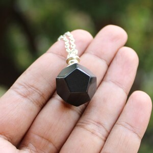 May include: A black geometric pendant necklace with a silver chain. The pendant is a dodecahedron, a 12-sided shape.