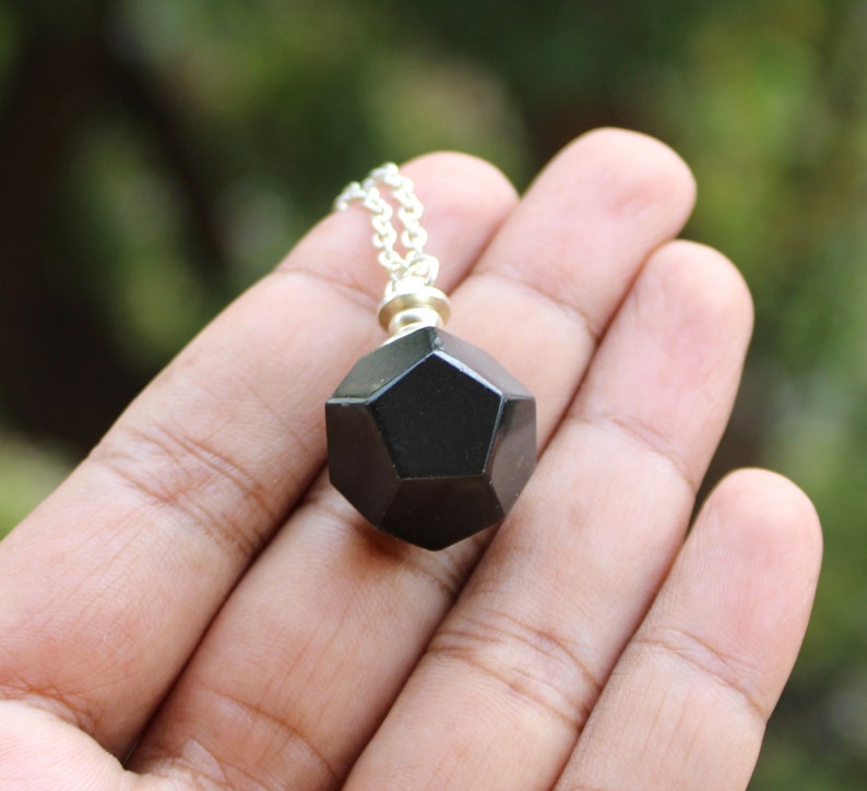May include: A black geometric pendant necklace with a silver chain. The pendant is a dodecahedron, a 12-sided shape.