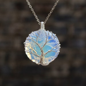 May include: A silver chain necklace with a pendant featuring a tree of life design crafted from wire and set in a clear, iridescent opal stone.