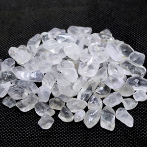 Puede incluir: Un montón de piedras de cuarzo claro pulidas sobre un fondo negro.