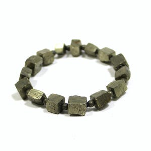 May include: A bracelet made of pyrite cubes, each cube is a dark gray color with a metallic sheen. The bracelet is strung on a thin silver chain.