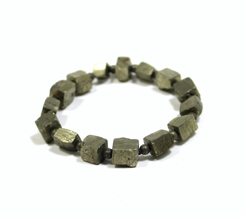May include: A bracelet made of pyrite cubes, each cube is a dark gray color with a metallic sheen. The bracelet is strung on a thin silver chain.
