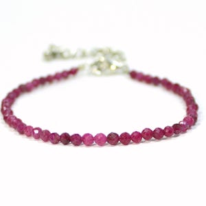 Könnte beinhalten: Ein zartes Armband aus rosafarbenen Edelsteinen mit einem silbernen Verschluss. Das Armband besteht aus kleinen, runden Perlen.