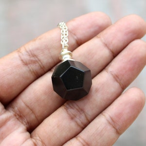 May include: A black gemstone pendant with a geometric shape, hanging from a silver chain.