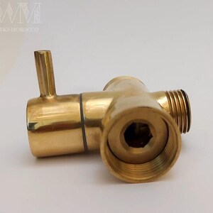 Puede incluir: Un accesorio de fontaner&iacute;a de lat&oacute;n de color dorado con tres salidas. El accesorio tiene una tuerca hexagonal en un lado y una salida redonda en el otro. El accesorio est&aacute; dise&ntilde;ado para conectar tuber&iacute;as o mangueras.