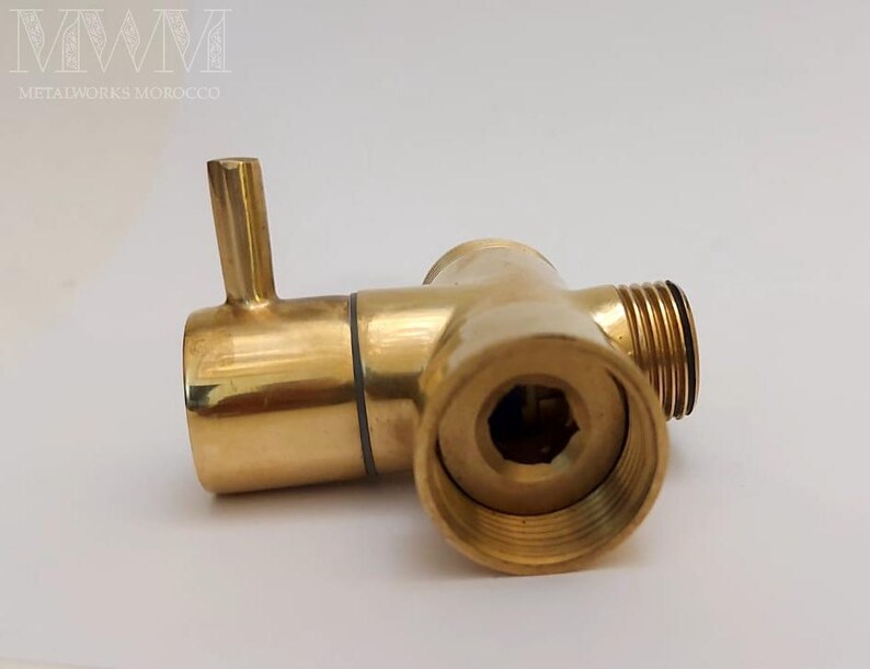Puede incluir: Un accesorio de fontaner&iacute;a de lat&oacute;n de color dorado con tres salidas. El accesorio tiene una tuerca hexagonal en un lado y una salida redonda en el otro. El accesorio est&aacute; dise&ntilde;ado para conectar tuber&iacute;as o mangueras.