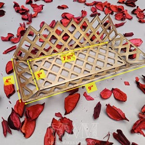 May include: A gold metal decorative tray with a diamond-shaped grid pattern. The tray measures 9 inches long, 7 1/2 inches wide, and 4 inches tall.