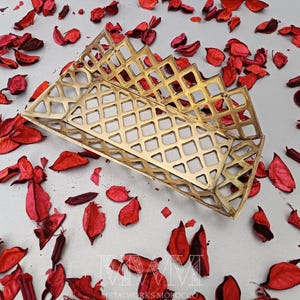May include: A gold metal decorative tray with a geometric pattern. The tray is made of a thin metal and has a rectangular shape.