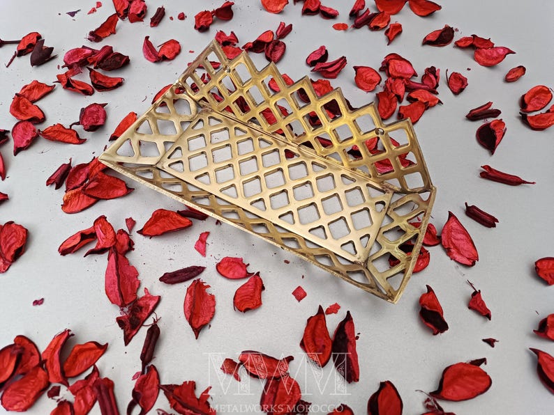 May include: A gold metal decorative tray with a geometric pattern. The tray is made of a thin metal and has a rectangular shape.