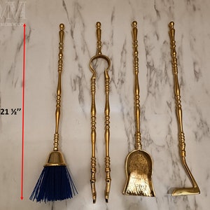 May include: Set of five gold-toned fireplace tools with decorative handles. The tools include a brush, tongs, shovel, poker, and a dustpan. The tools are 21 1/2 inches long.