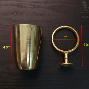 May include: A gold metal cup holder with a 3-inch diameter ring and a 4 1/4-inch height. The cup holder is made of solid brass and has a polished finish.