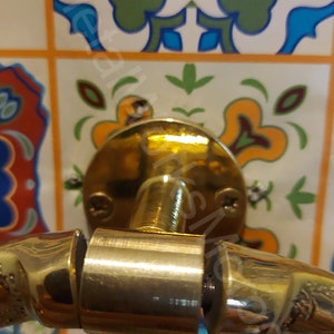 K&ouml;nnte beinhalten: Ein goldfarbener Handtuchring mit einem dekorativen, strukturierten Design. Der Ring ist mit einer runden, flachen Basis an einer Wand befestigt.
