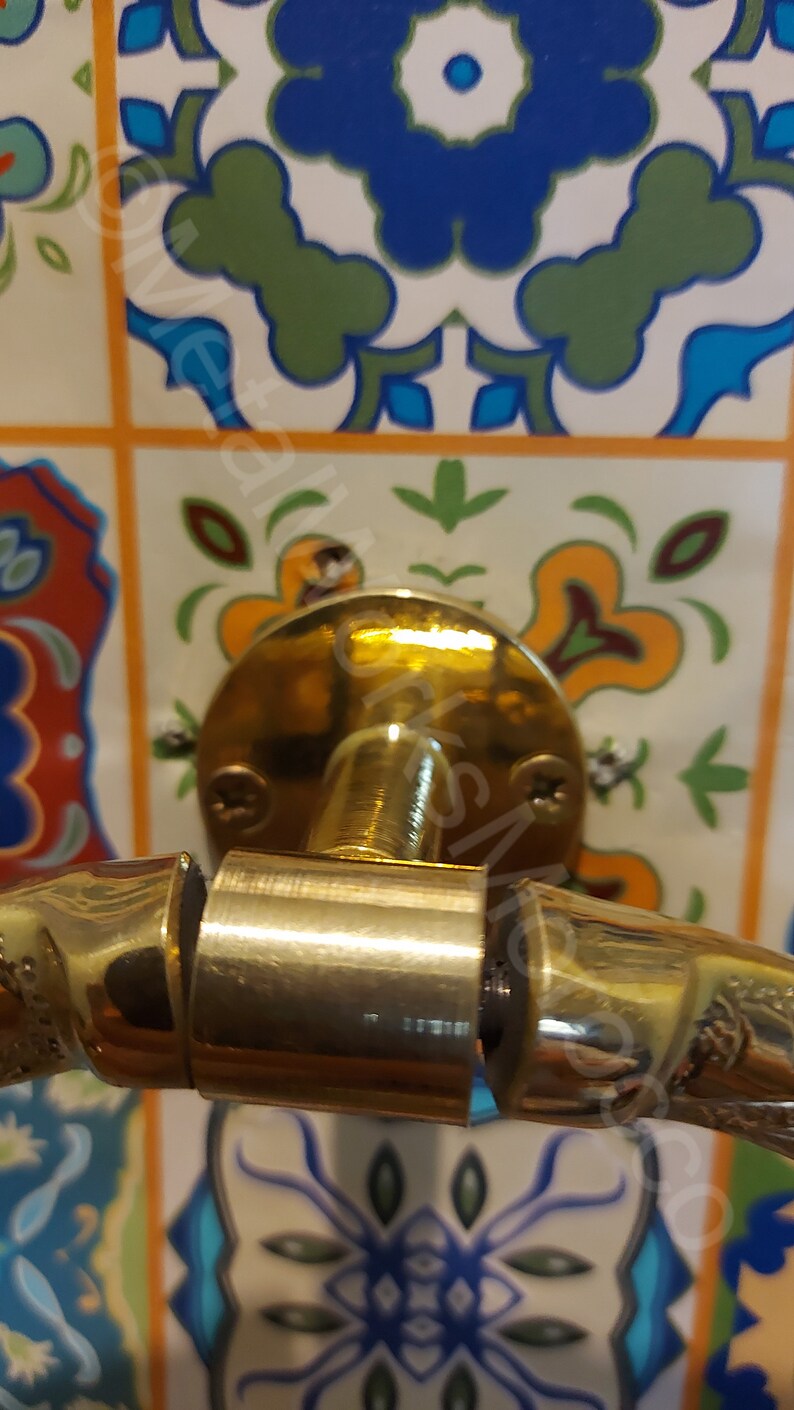 K&ouml;nnte beinhalten: Ein goldfarbener Handtuchring mit einem dekorativen, strukturierten Design. Der Ring ist mit einer runden, flachen Basis an einer Wand befestigt.