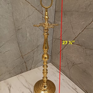 May include: Gold metal umbrella stand with a round top and a decorative base. The stand is 27 1/2 inches tall.