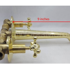 May include: Brass wall-mounted faucet with two cross-shaped handles and a 23 cm spout.