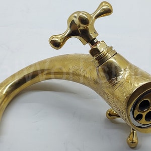 Op de afbeelding: Een messing kraan in vintage-stijl met een sierlijk ontwerp. De kraan heeft een gebogen uitloop, een kruisvormige hendel en decoratieve details. De messing afwerking geeft het een klassieke, elegante uitstraling.