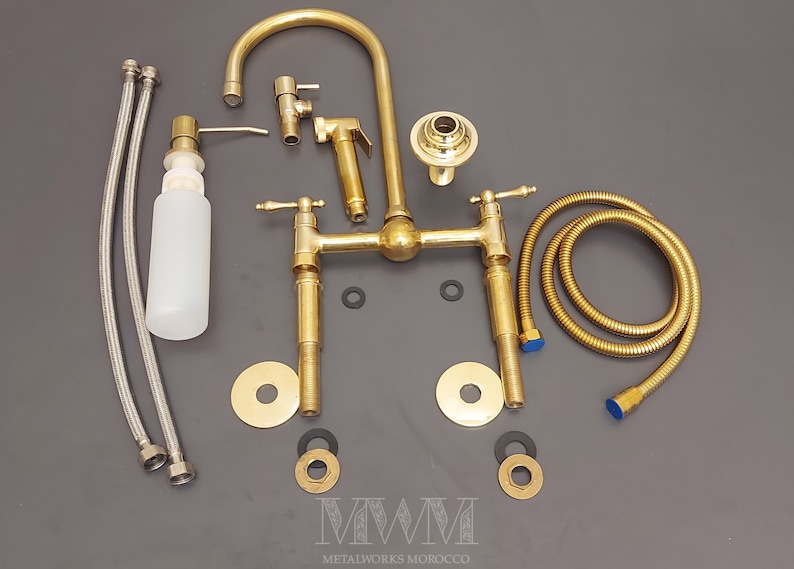 May include: A gold-toned bathroom faucet set with two handles, a spout, a hand shower, and a soap dispenser. The set includes two hoses, two washers, and two decorative plates.