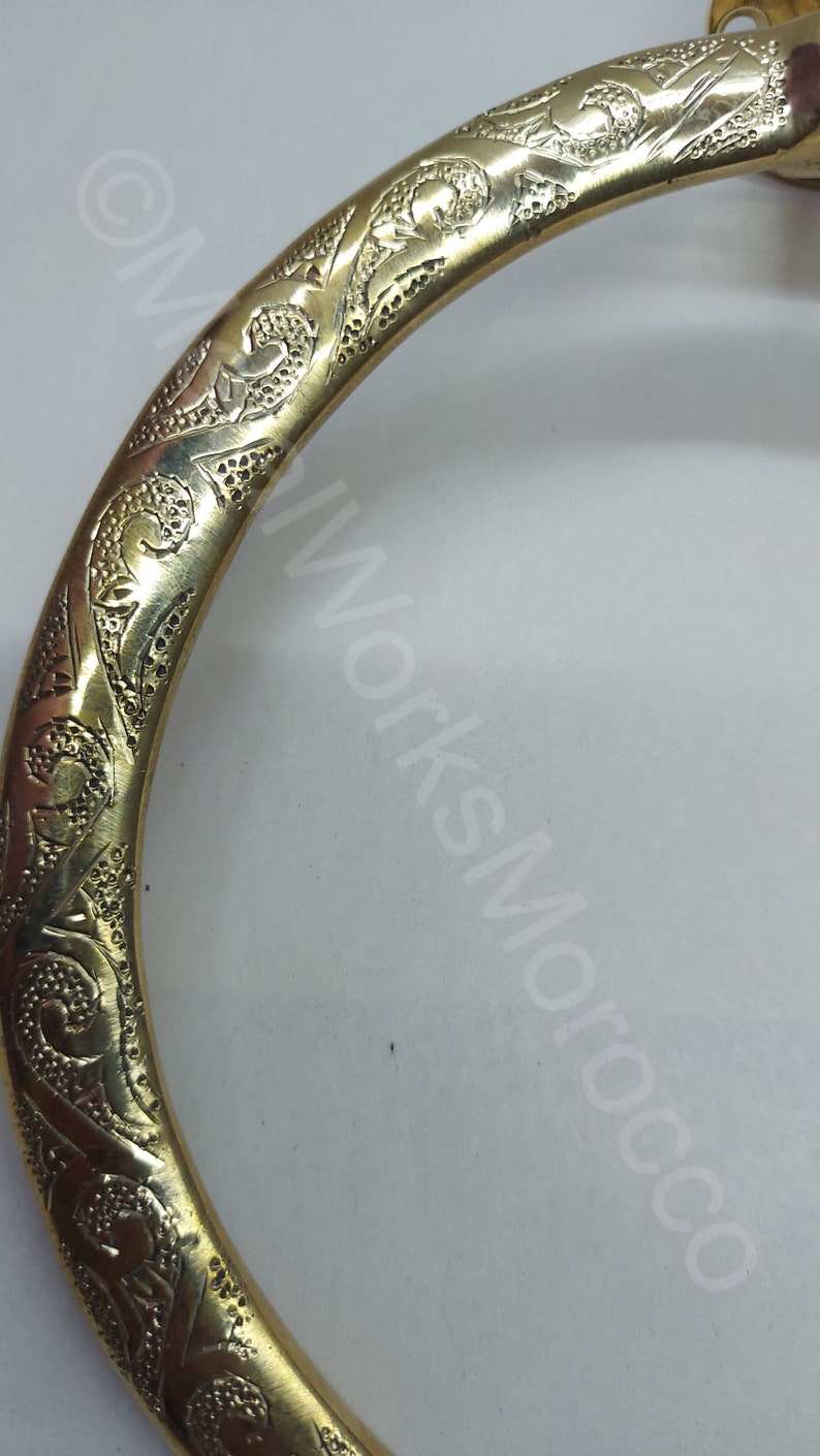 K&ouml;nnte beinhalten: Ein goldfarbener Handtuchring aus Metall mit einem komplizierten, gravierten Blumendesign.