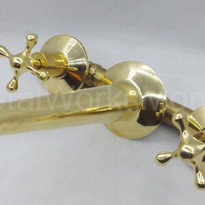 May include: A polished brass faucet with two cross-shaped handles and a curved spout.