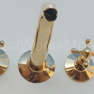 May include: A gold-toned bathroom faucet with two cross-shaped handles and a spout.