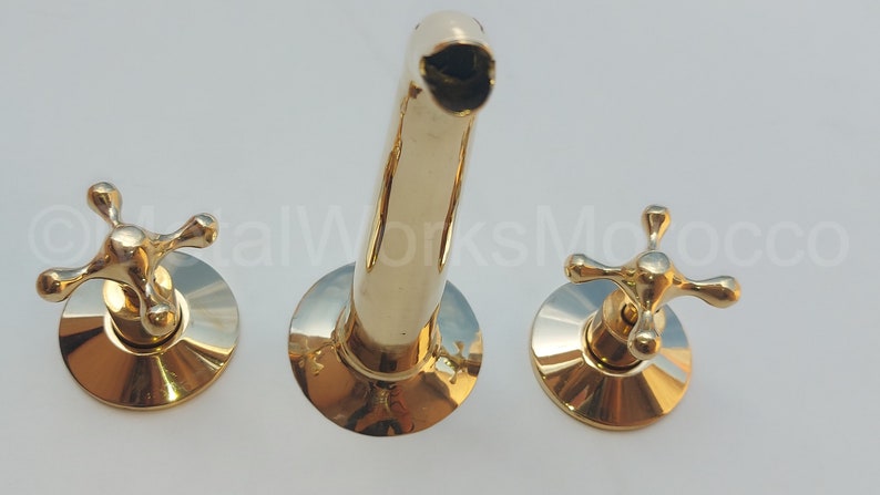 May include: A gold-toned bathroom faucet with two cross-shaped handles and a spout.