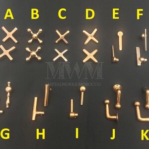May include: A collection of gold-toned metal faucet handles and knobs labeled A through K. The set includes various cross-shaped, lever, and L-shaped designs, each featuring a polished metallic finish and distinct structural configurations.