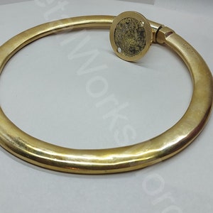 K&ouml;nnte beinhalten: Ein massiver Messingring mit glatter, polierter Oberfl&auml;che. Der Ring ist an einer runden Basis mit einer Schraube befestigt.