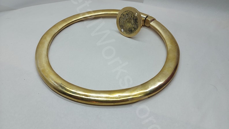 K&ouml;nnte beinhalten: Ein massiver Messingring mit glatter, polierter Oberfl&auml;che. Der Ring ist an einer runden Basis mit einer Schraube befestigt.