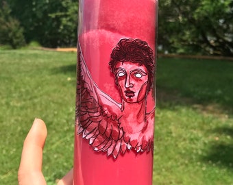 May include: A pink glass candle with a white angel with wings and a red halo. The angel has a white face and black hair.