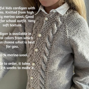 May include: A light gray knitted cardigan with pearl buttons. The cardigan has a cable knit pattern and is made from 100% merino wool. The text "Beautiful kids cardigan with buttons. Knitted from high quality merino wool. Good choice for school outfit. Very soft texture. Cardigan is available in several colors from which you can choose what is best for you. 100% merino wool. Made to order, it takes about 2-4 weeks to make it." is visible in the image.