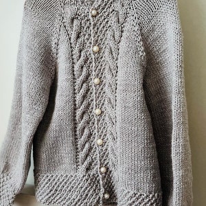 May include: A gray knitted cardigan with a cable knit pattern and pearl buttons.