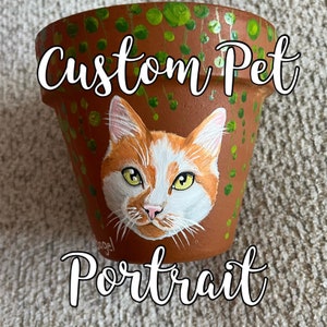 May include: A terracotta flower pot with a painted portrait of an orange and white cat. The pot is decorated with green vines and the words "Custom Pet Portrait" are written across the top.