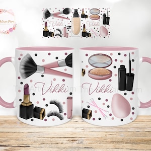 Peut inclure: Une tasse en c&eacute;ramique blanche avec un bord et une poign&eacute;e roses. La tasse pr&eacute;sente un motif de pois roses et noirs avec des illustrations de maquillage, notamment des pinceaux, du rouge &agrave; l&egrave;vres, de l'eye-liner et une &eacute;ponge &agrave; maquillage. Le nom "Vikki" est &eacute;crit en noir sur la tasse.