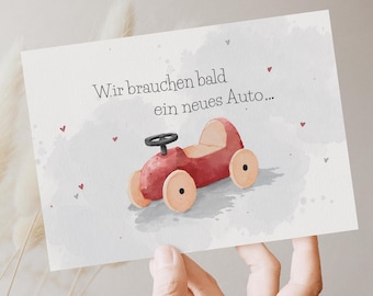 May include: A rectangular greeting card featuring a watercolour illustration of a red toy car with light wooden wheels and a black steering wheel. The text reads Wir brauchen bald ein neues Auto... surrounded by small red hearts on a grey background.