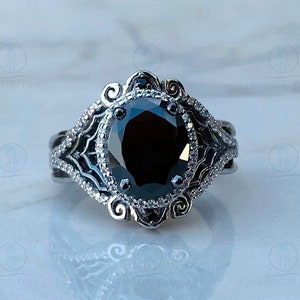 May include: A black diamond engagement ring with a silver band and intricate filigree detailing. The ring features a large, round black diamond surrounded by smaller diamonds.