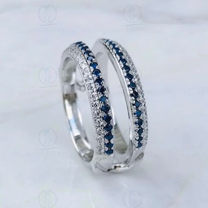 May include: A pair of silver rings with a double row of blue and white stones. The rings are designed to be worn together, with one ring fitting inside the other.