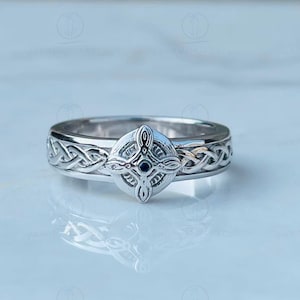 May include: A silver ring with a Celtic knot design and a small blue gemstone in the center.