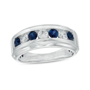 May include: A silver-toned ring featuring a row of alternating round, dark blue and clear gemstones. The ring has a smooth, polished band and a channel setting for the gemstones. The gemstones are evenly spaced across the top of the ring.