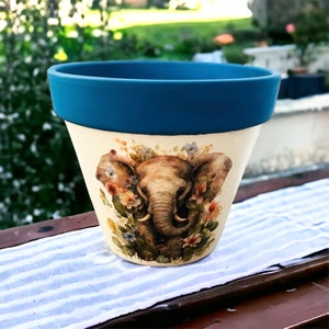 May include: A blue and white ceramic planter featuring an elephant design. The elephant is surrounded by flowers and foliage.