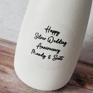 May include: White ceramic vase with black text that reads "Happy Silver Wedding Anniversary Mandy & Scott".