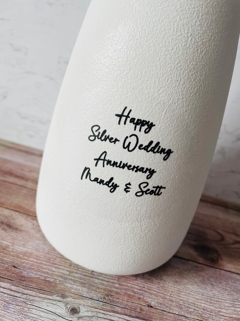 May include: White ceramic vase with black text that reads "Happy Silver Wedding Anniversary Mandy & Scott".