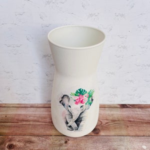 May include: White ceramic vase with a watercolor design of two elephants with pink flowers and green leaves.