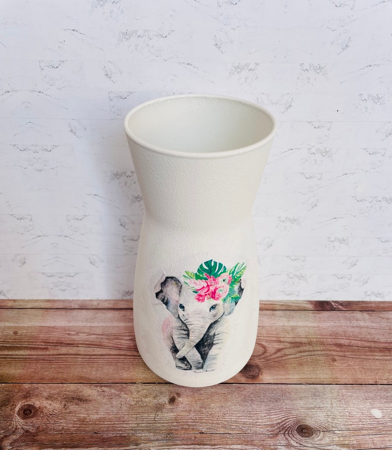 May include: White ceramic vase with a watercolor design of two elephants with pink flowers and green leaves.