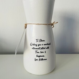 May include: White ceramic vase with a message that reads "To Claire. Wishing you a wonderful retirement filled with Fun, love & happiness.. Love Katherine."