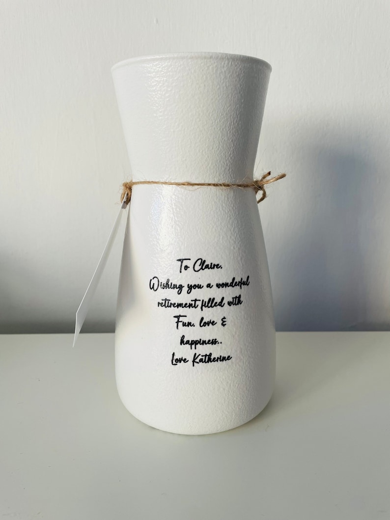 May include: White ceramic vase with a message that reads "To Claire. Wishing you a wonderful retirement filled with Fun, love & happiness.. Love Katherine."