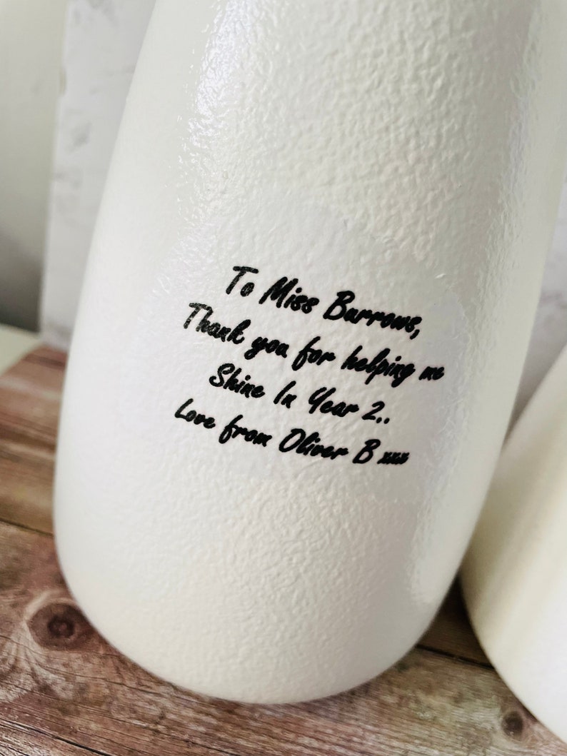 May include: White ceramic vase with a handwritten message that reads "To Miss Burrows, Thank you for helping me Shine In Year 2.. Love from Oliver B xus".