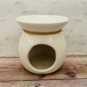 May include: White ceramic wax warmer with a round opening and a rope accent around the top.