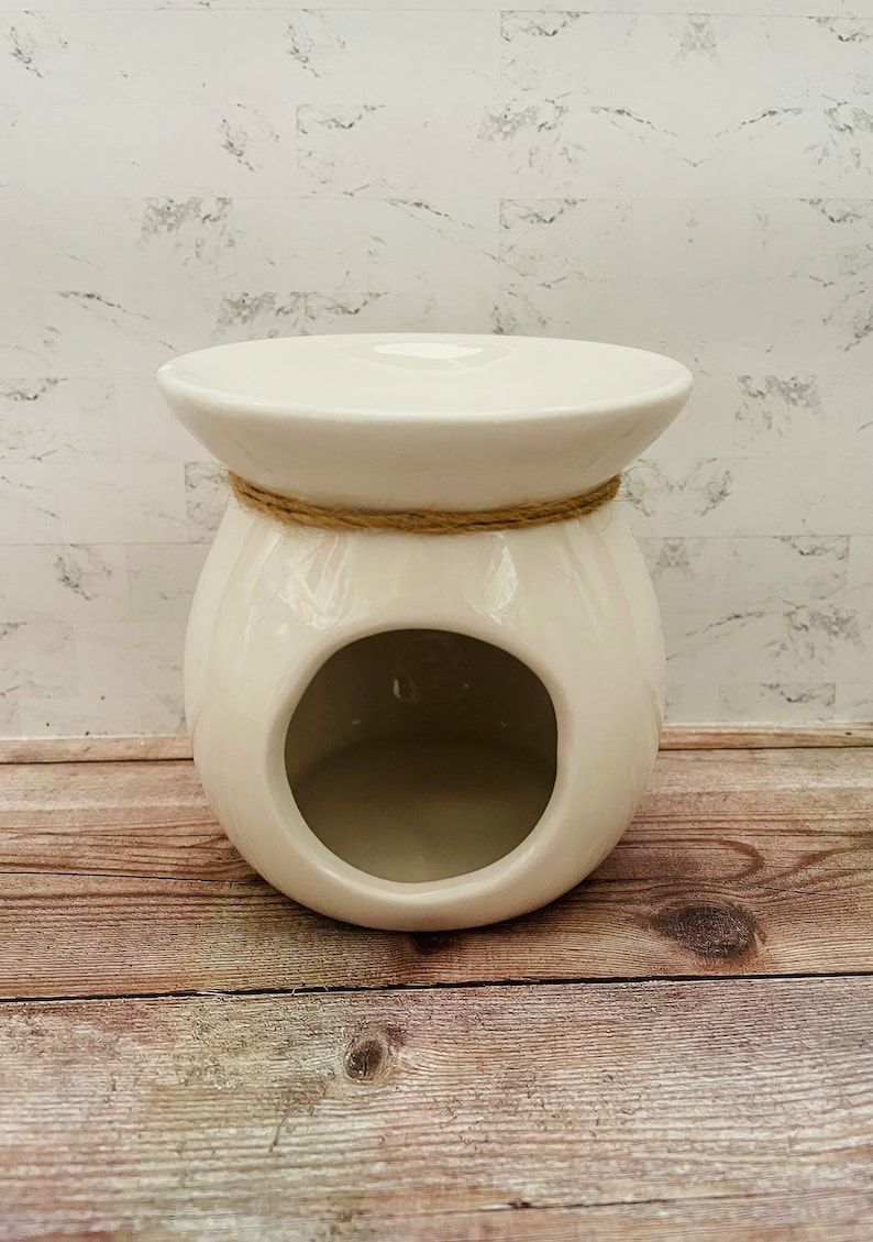 May include: White ceramic wax warmer with a round opening and a rope accent around the top.