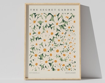 May include: A framed print with a white background featuring a pattern of white Shasta daisies with yellow centers on a green background. The text "THE SECRET GARDEN" is at the top of the print and "SEPTEMBER... SHASTA DAISY" is at the bottom.